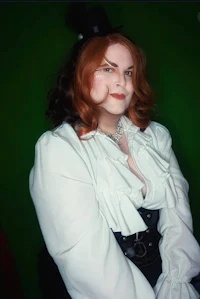 a woman with red hair and a top hat is posing for a photo